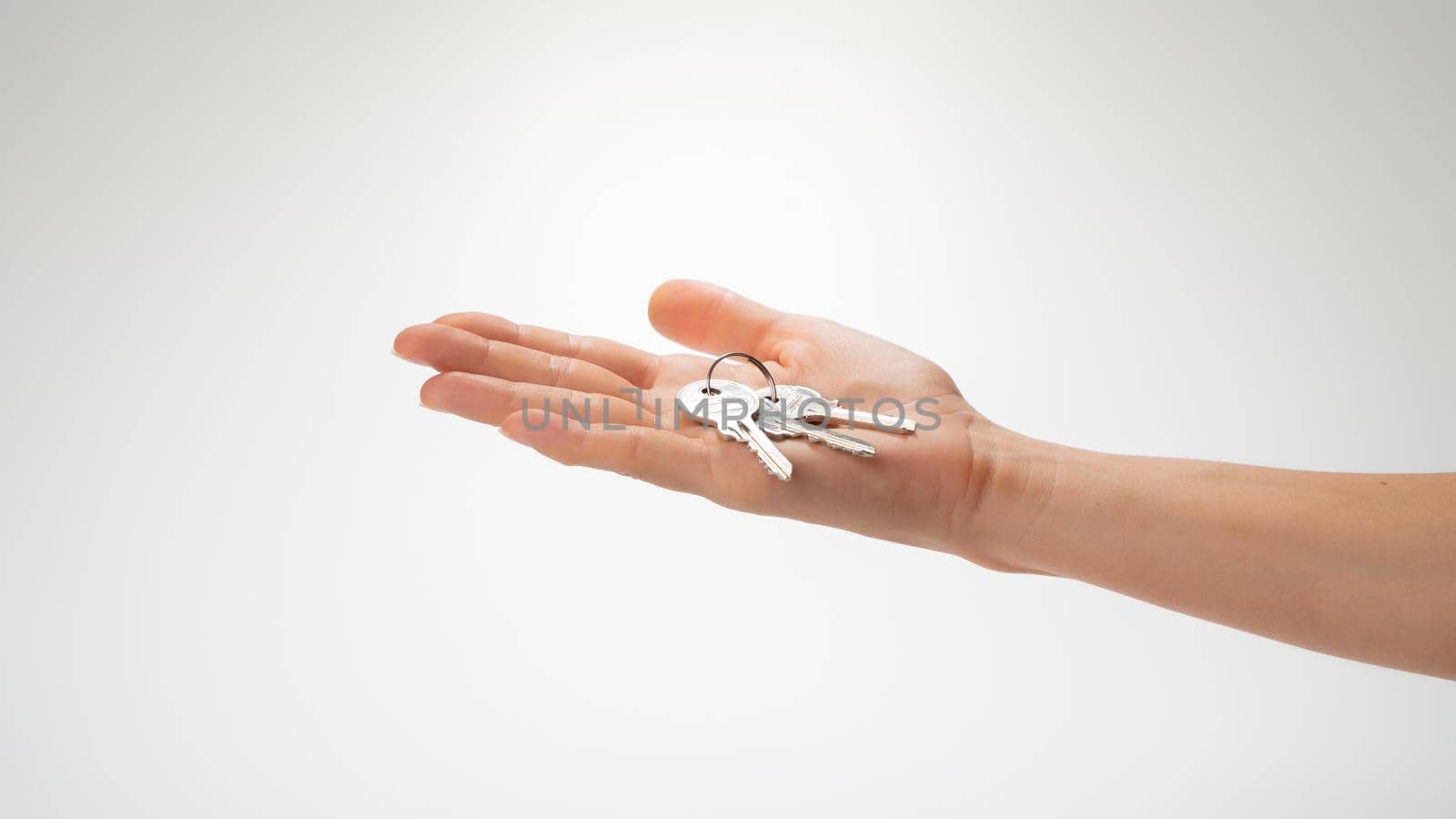 A bunch of keys lies on a woman's palm on a white background. High quality photo