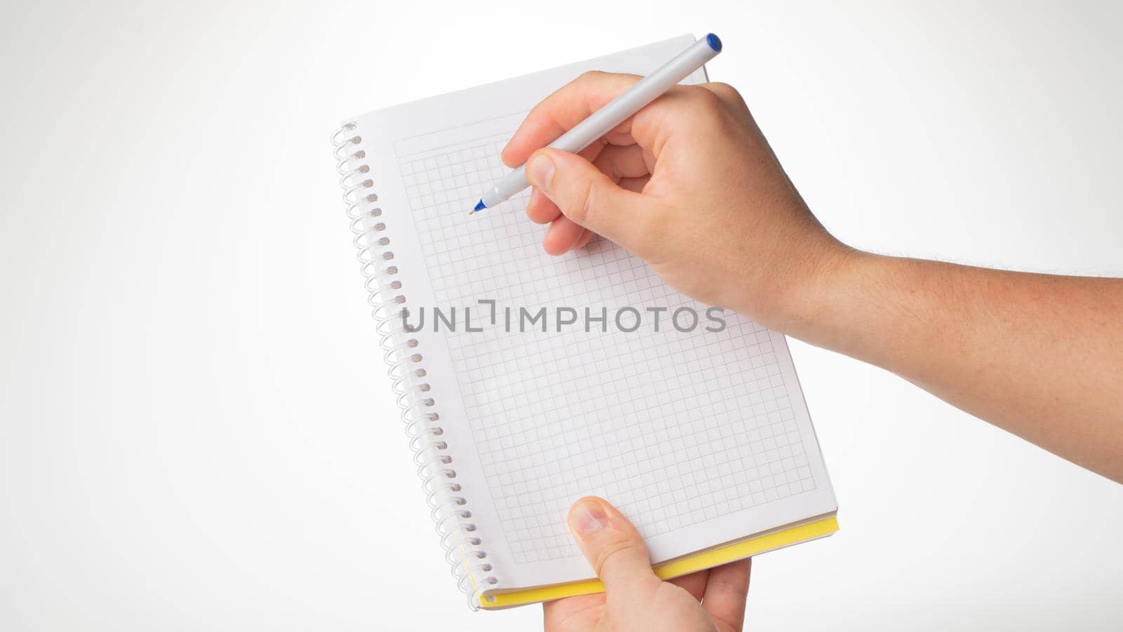 men's hand hold a notebook, a pen in her right hand writes in a notebook in a cage. High quality photo