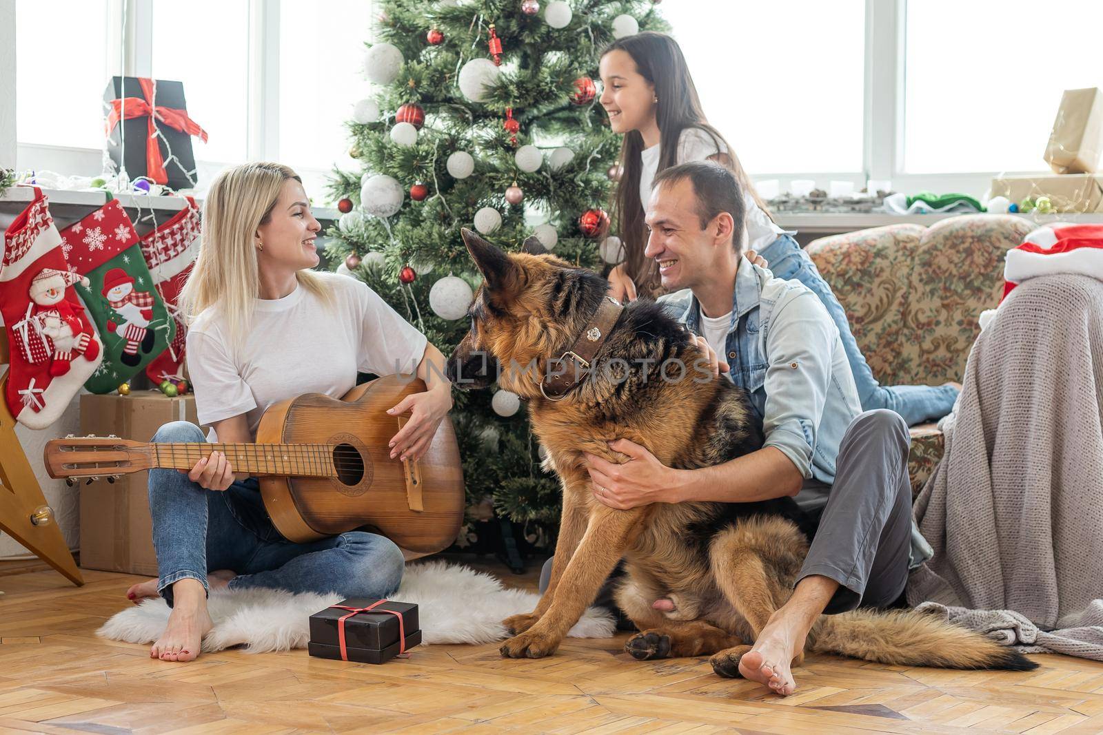happy family and cute dog having fun at christmas tree. atmospheric emotional moments. merry christmas and happy new year concept
