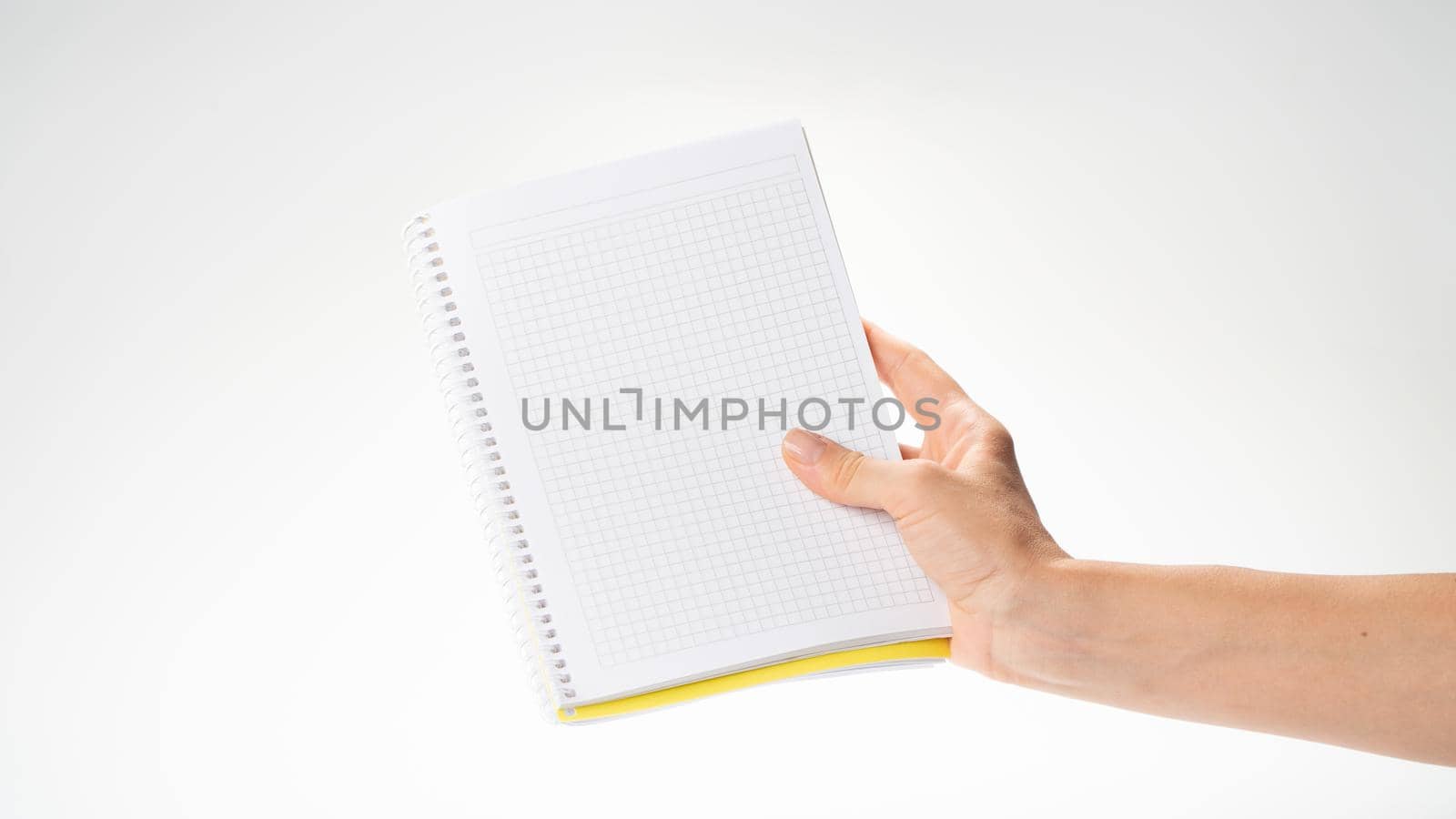 A woman's right hand holds a notebook in a cage on a white background space for inscription by voktybre