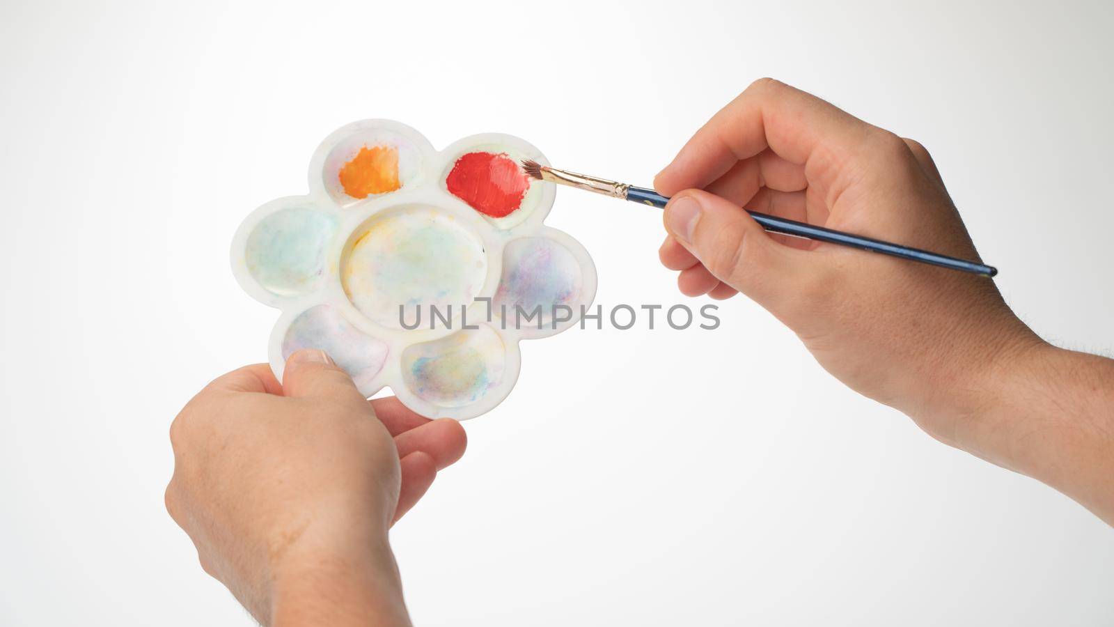 men's hands with palette and brush, gesture to mix paint by voktybre