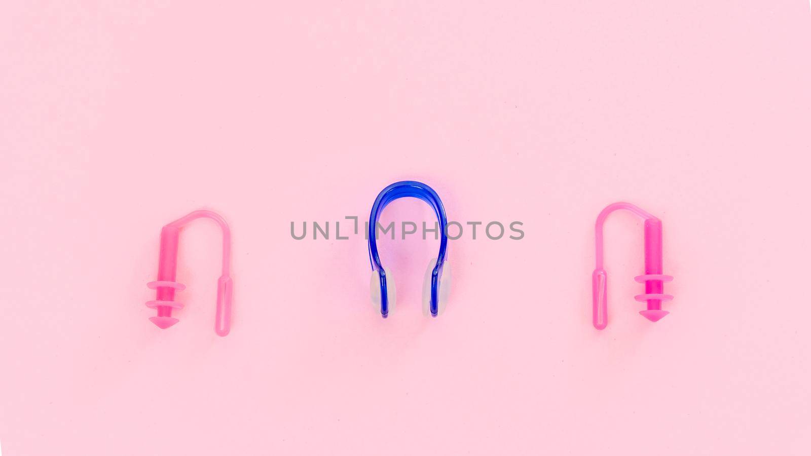 Swimmer set - earplugs and nose clip on pink background close-up. High quality photo