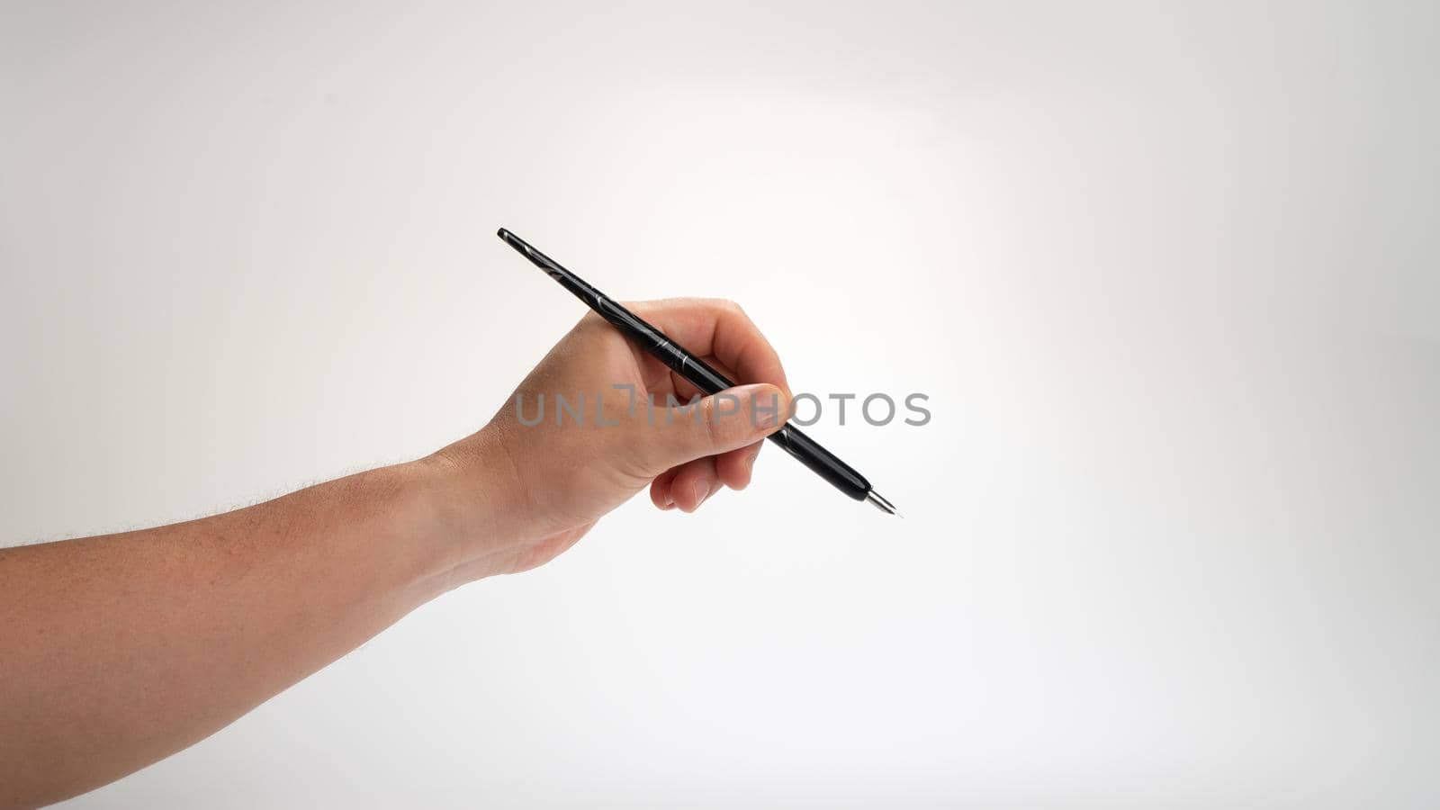 men's left hand holds a calligraphy pen on a white background, gesture drops into the inkwell. High quality photo