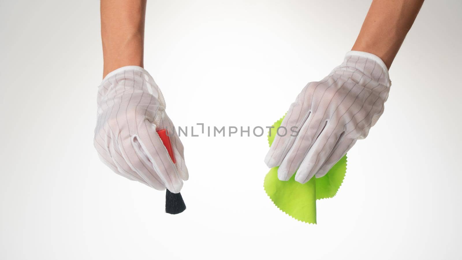 Gloved hands with a brush and a green cloth for cleaning equipment. High quality photo