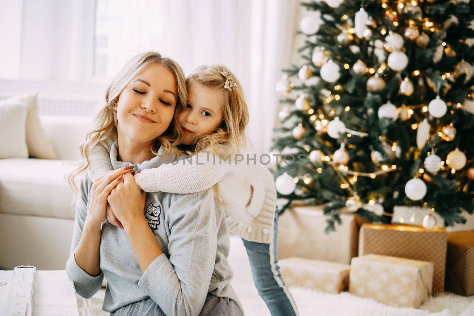 Happy family: mother and daughter. Family in a bright New Year's interior with a Christmas tree.