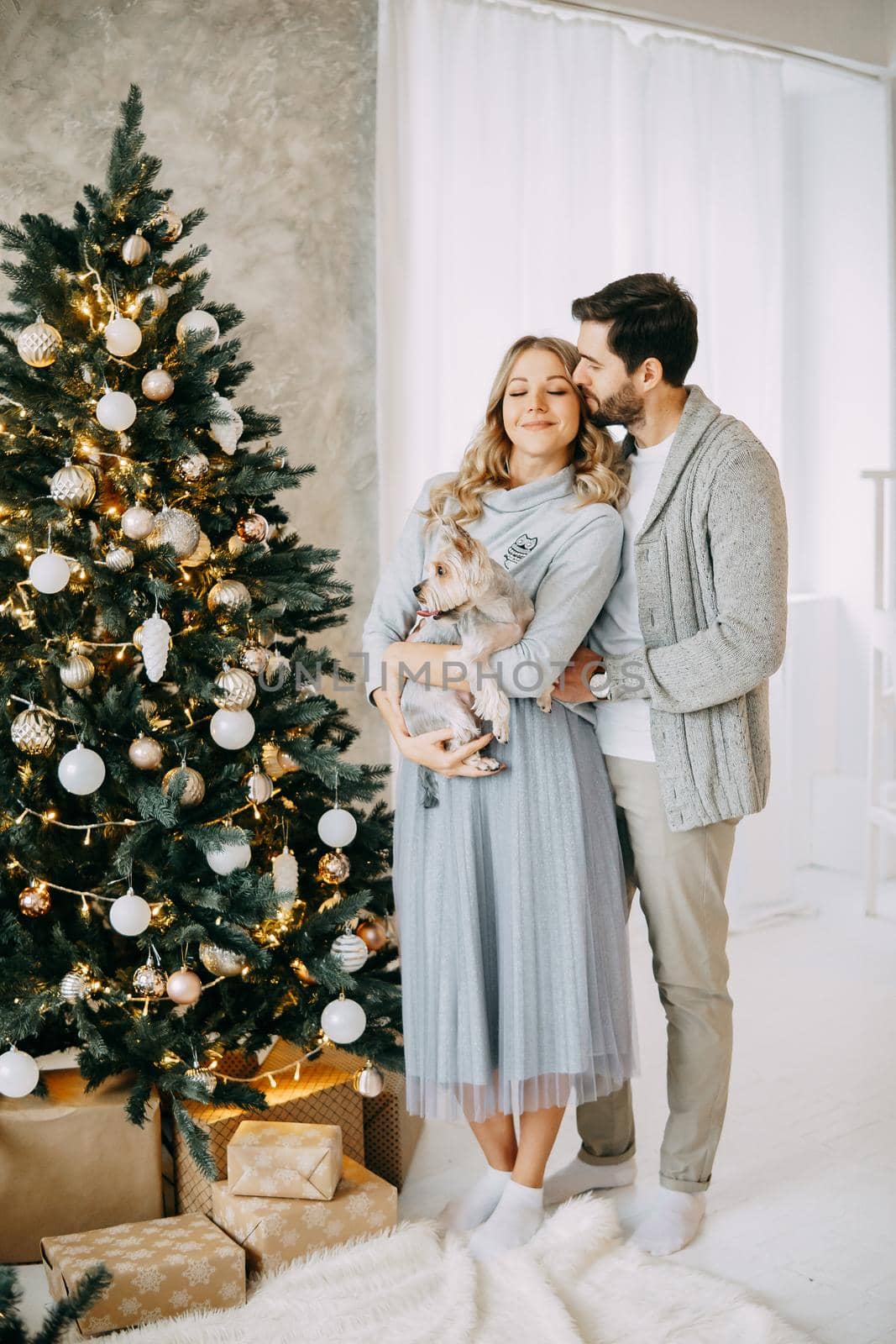 Happy family: mom, dad and pet. Family in a bright New Year's interior with a Christmas tree by Annu1tochka