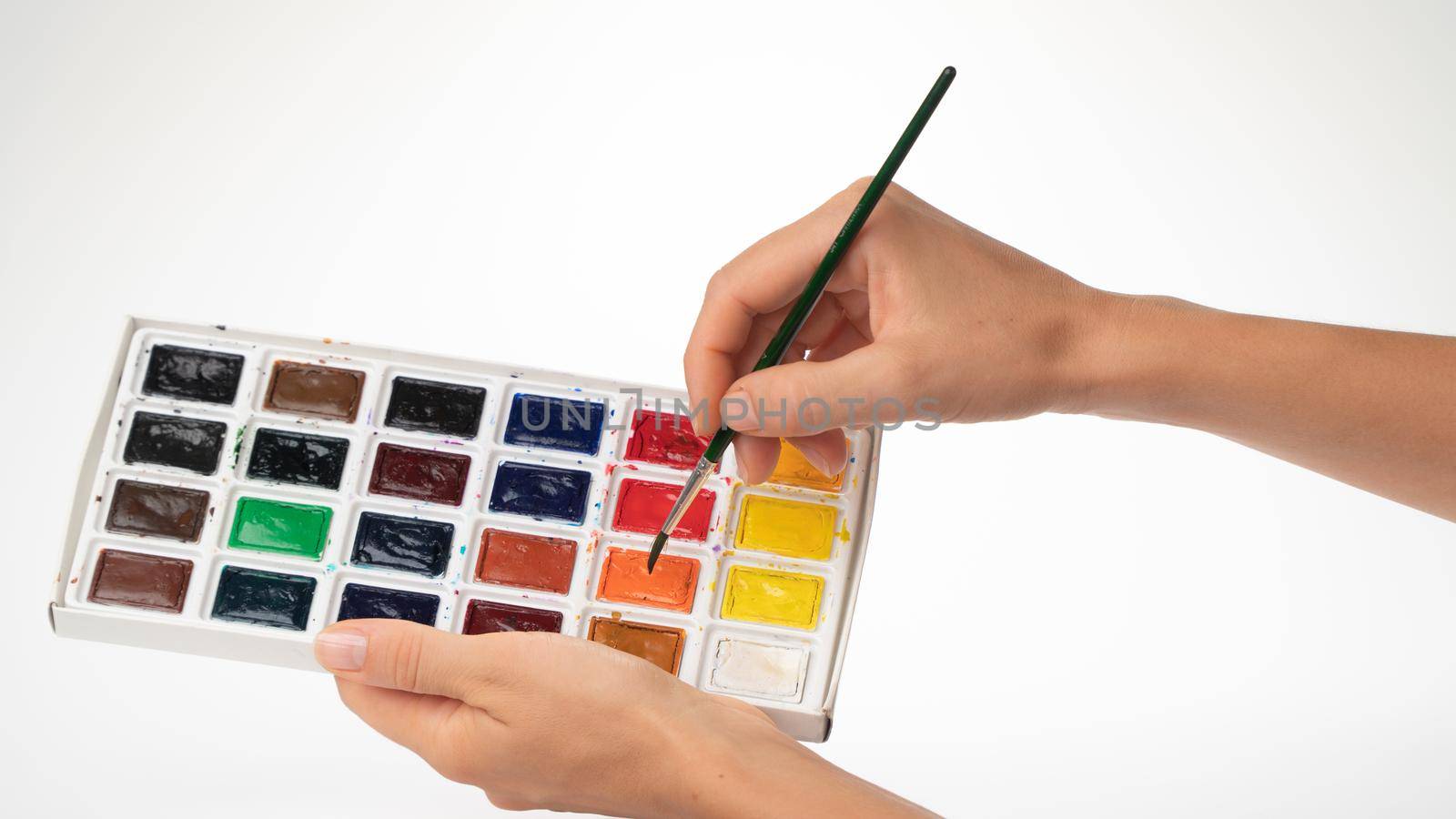 Watercolor paints and brush in women's hands gesture to dial paint on a brush by voktybre