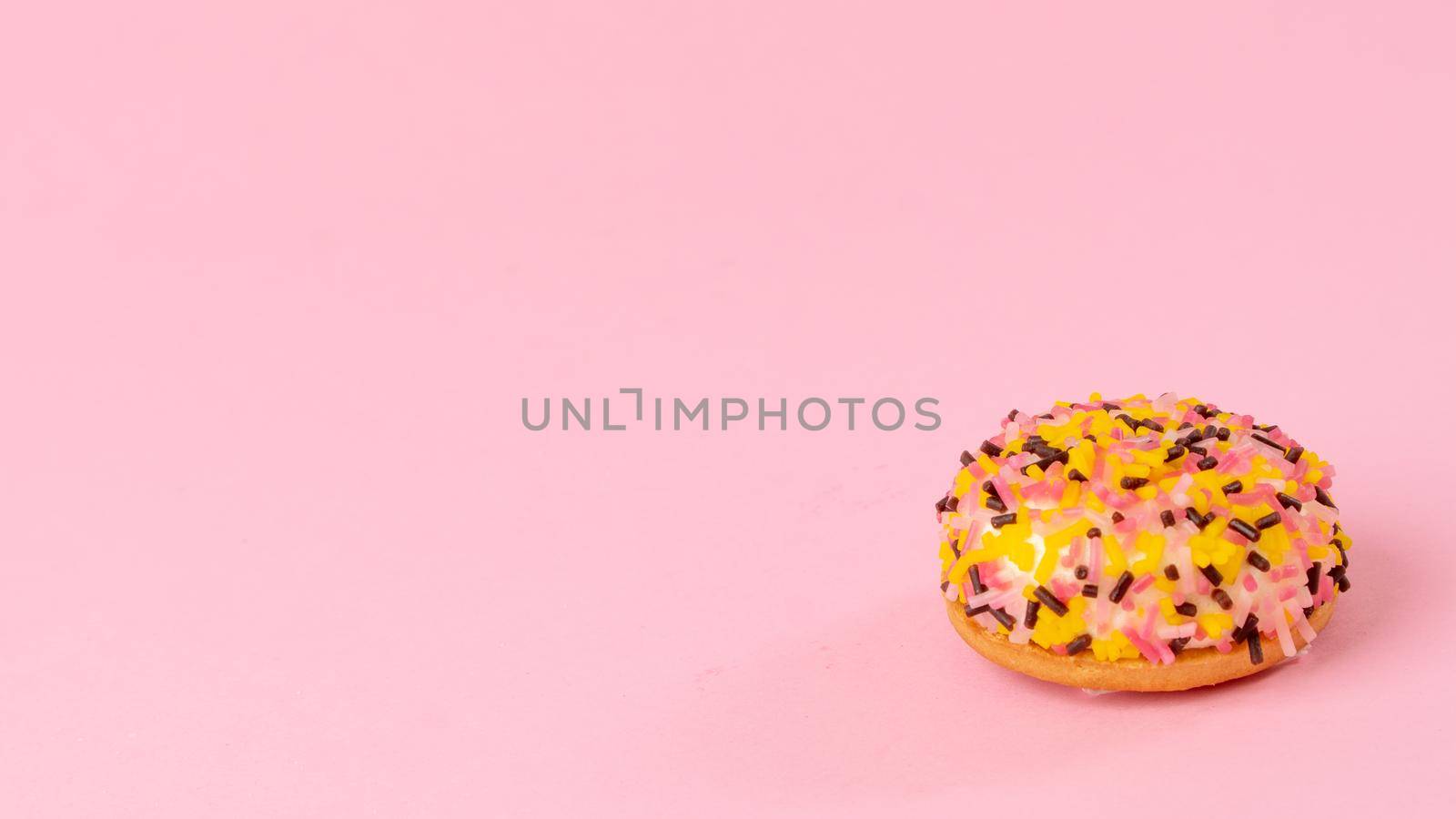 Cake with multi-colored sprinkling on a pink background. High quality photo