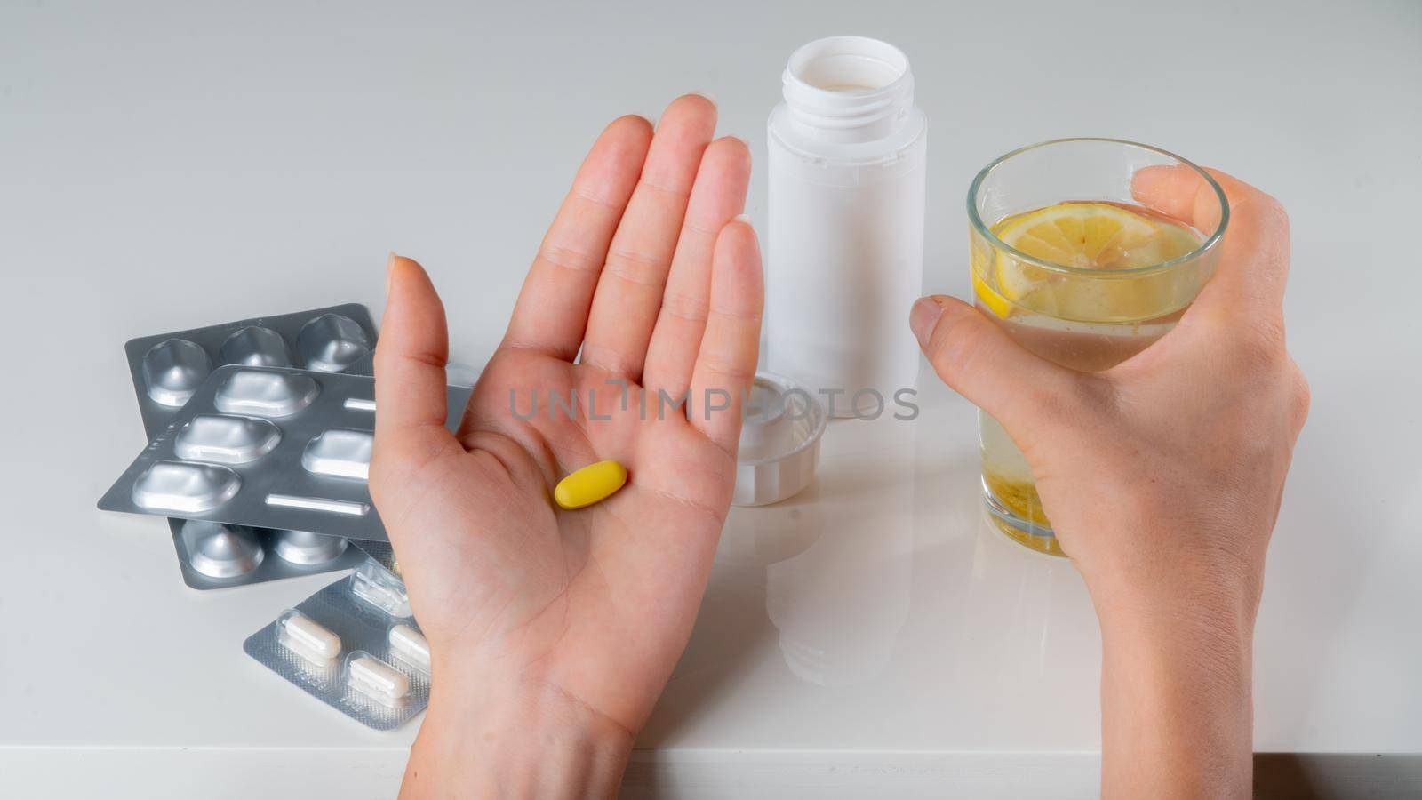 Pill tablet and a glass of water and lemon in your hands against the background of cold medicines. High quality photo