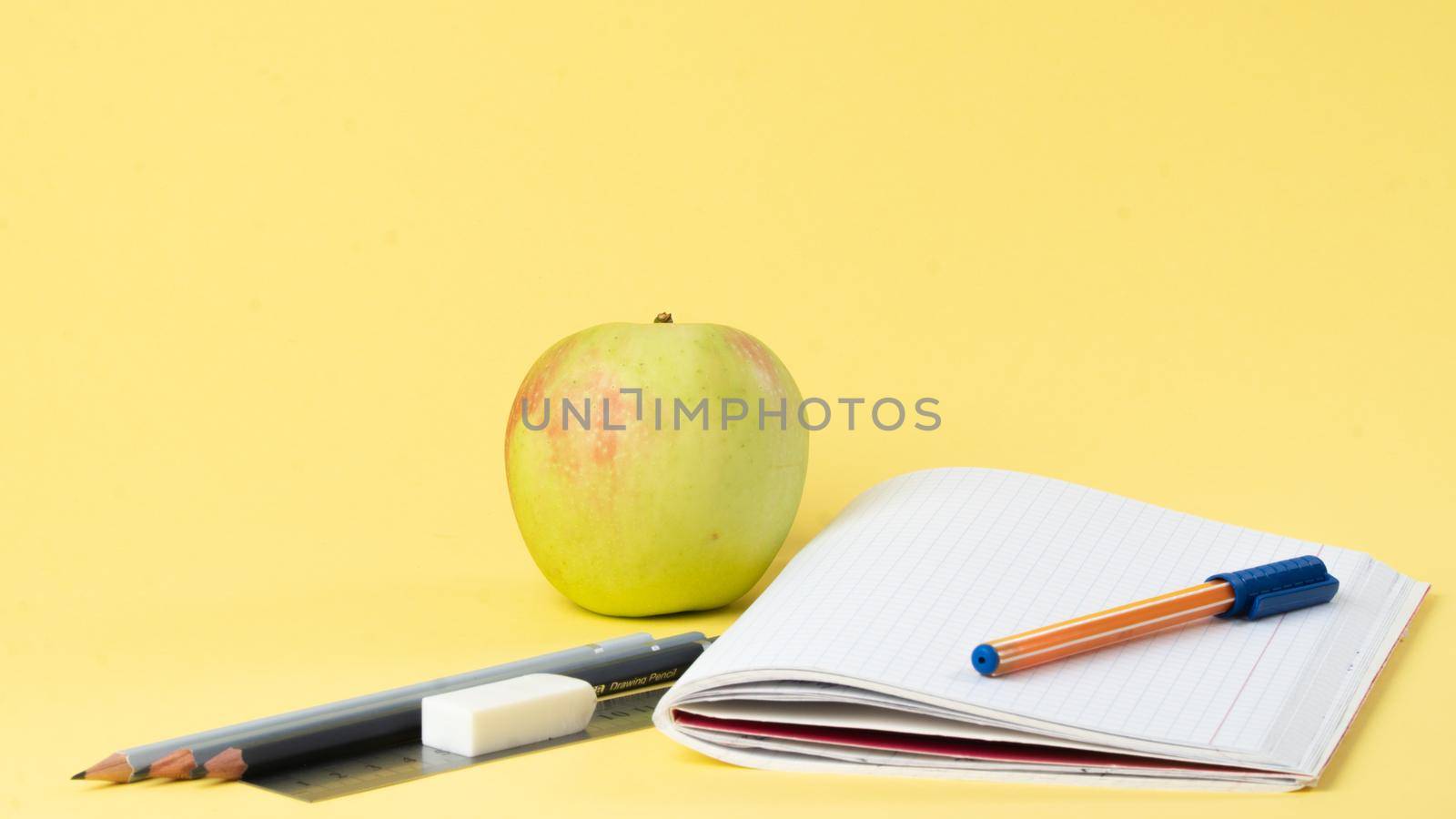 Workbook with pen and pencils for studying, apple for a snack by voktybre