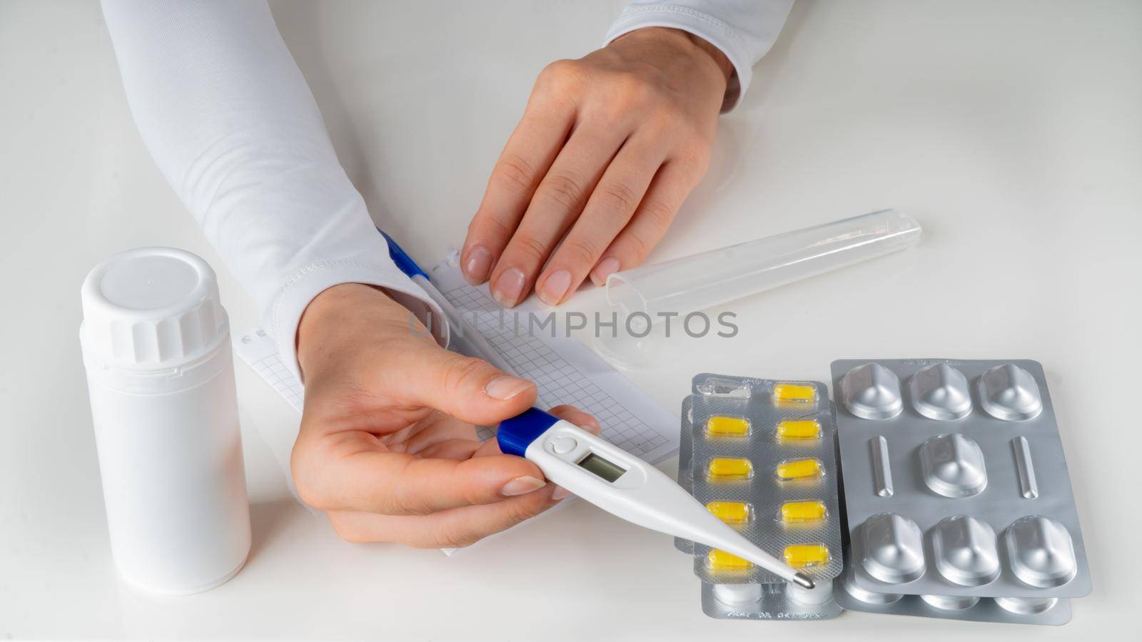 The doctor's hands stretch out a thermometer against the background of tablets. High quality photo