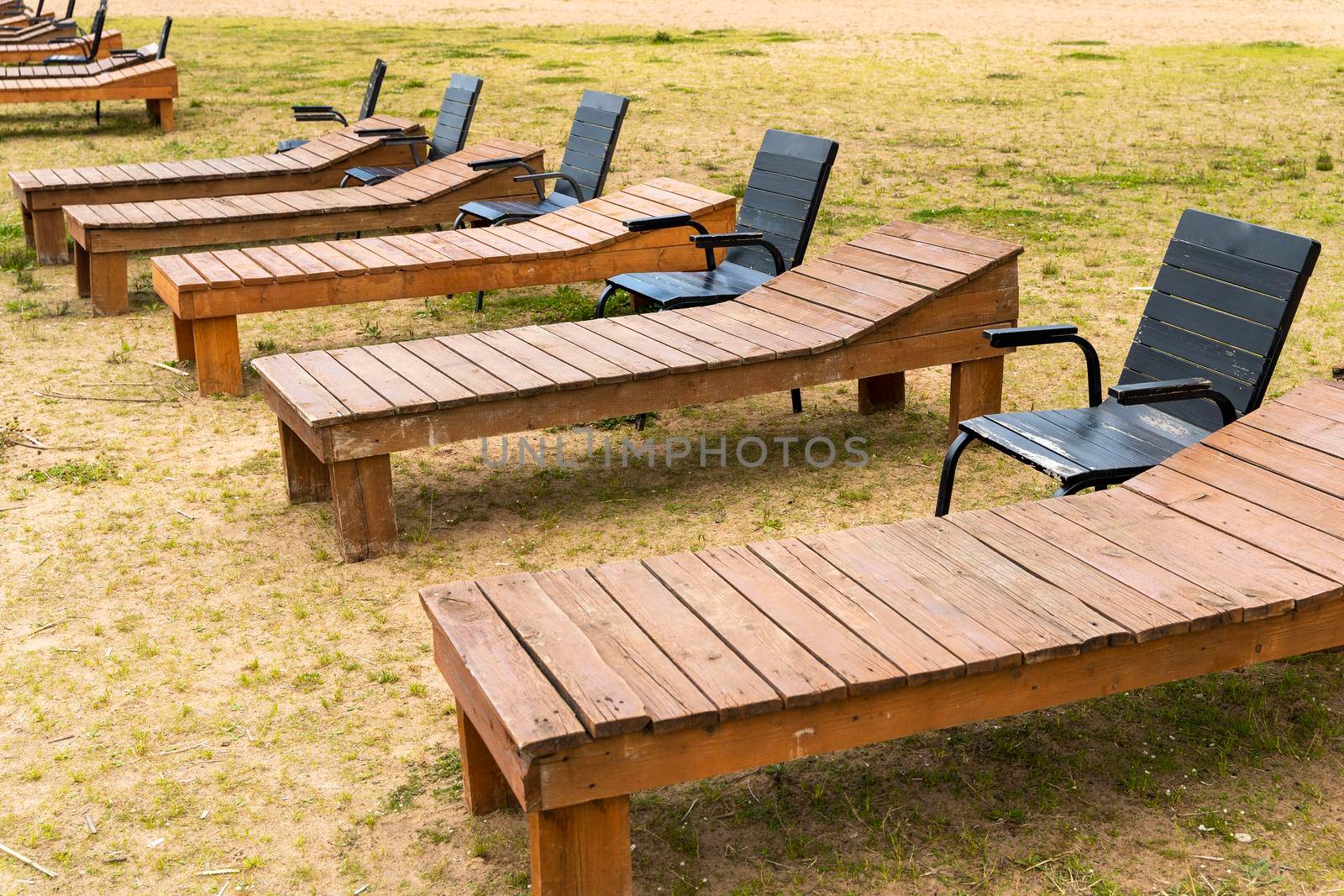 wooden deck chairs and chairs on the sandy beach of the lake. Summer beach holidays