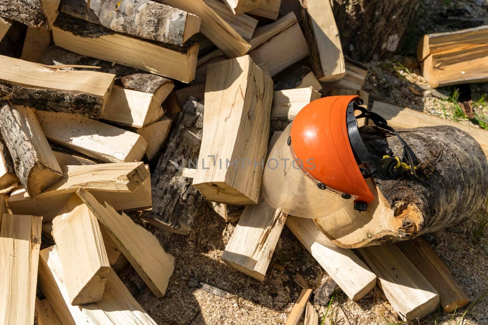 a pile of chopped firewood in the yard of the house and a protective mask to protect the eyes during chopping and sawing firewood