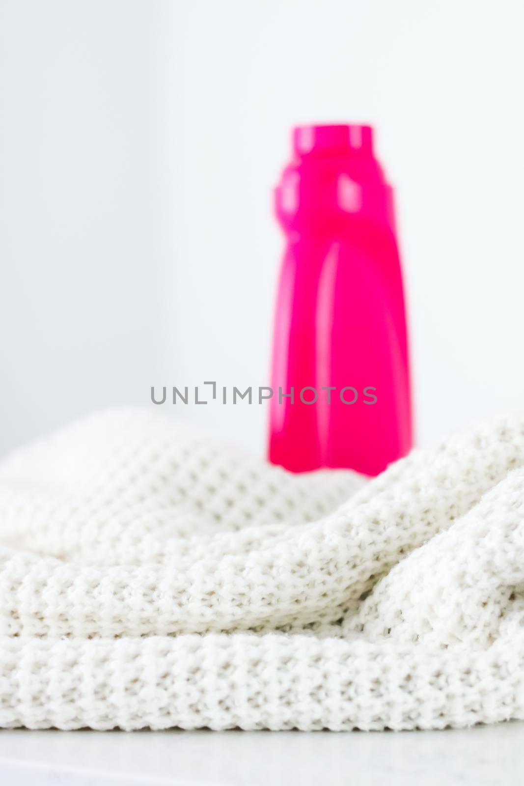 Housekeeping, fabric textures and handmade knitwear concept - Warm knitted clothes and liquid laundry detergent