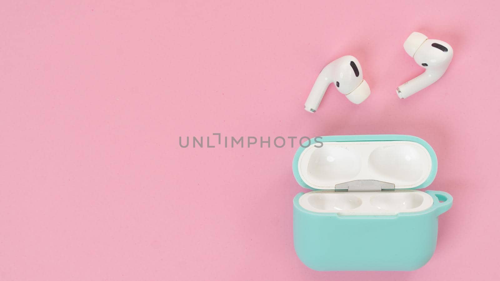 Wireless headphones in mint case on pink background, delicate background shades with space for text by voktybre