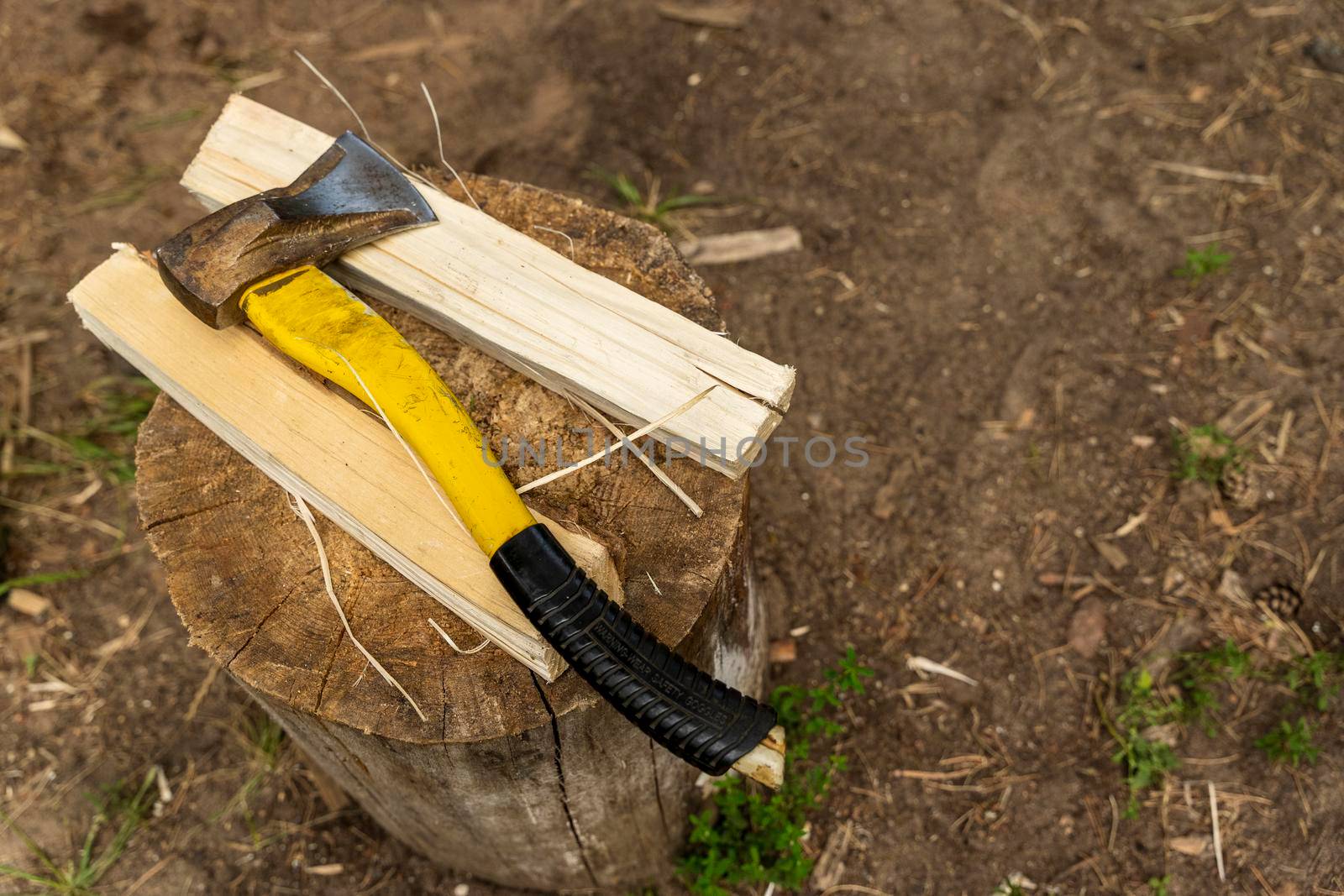 an axe with a plastic handle and a split wooden log on a stump on the street. Chopping wood