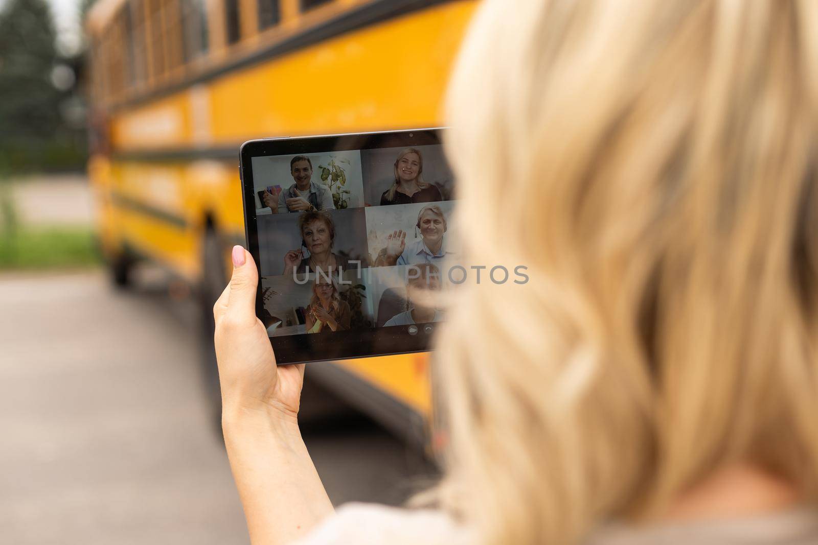 Female Teacher Or Student With Digital Tablet near the school bus. video chat.