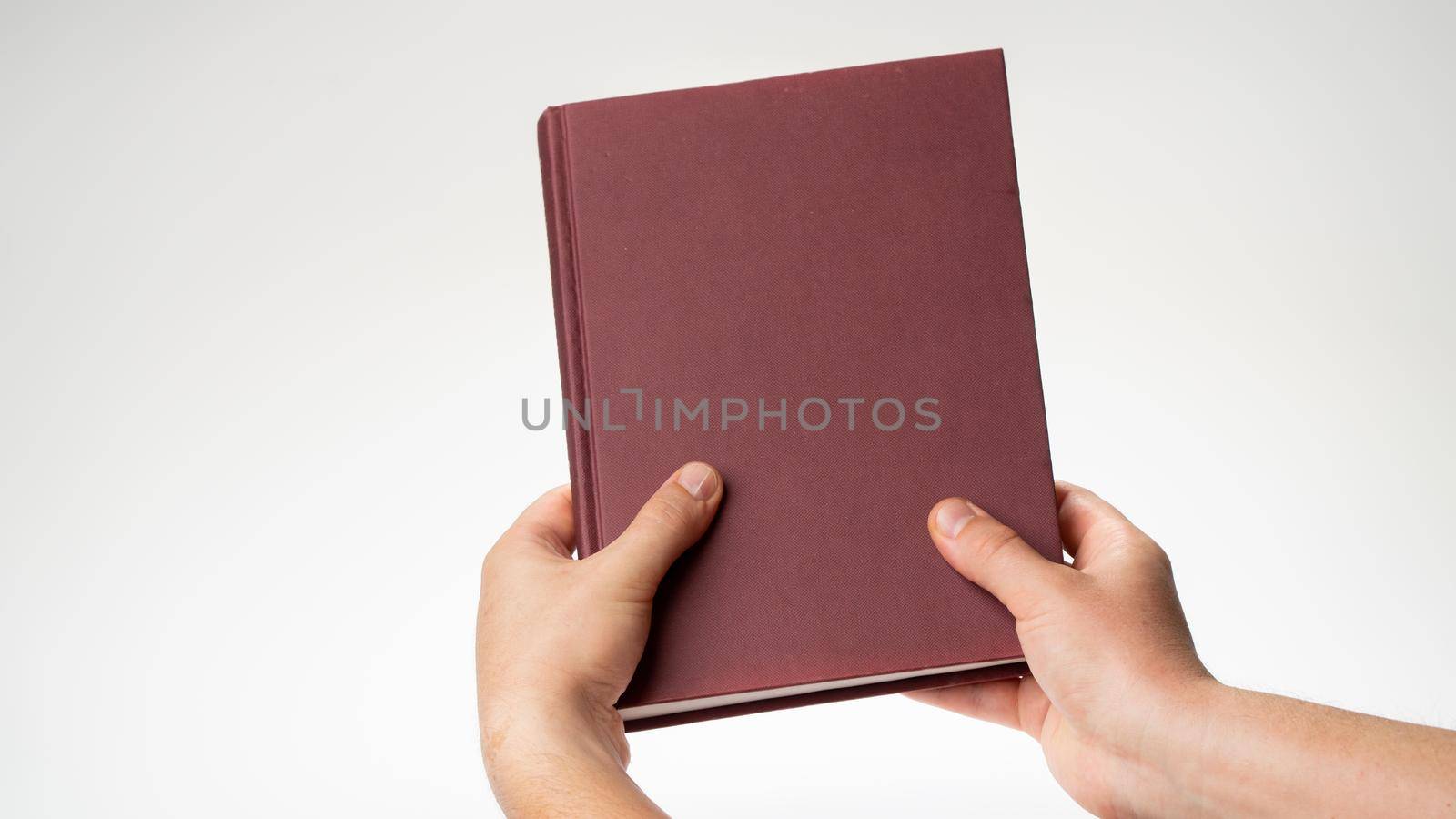 Men's hands hold a book or notebook in a burgundy binding on a white background by voktybre