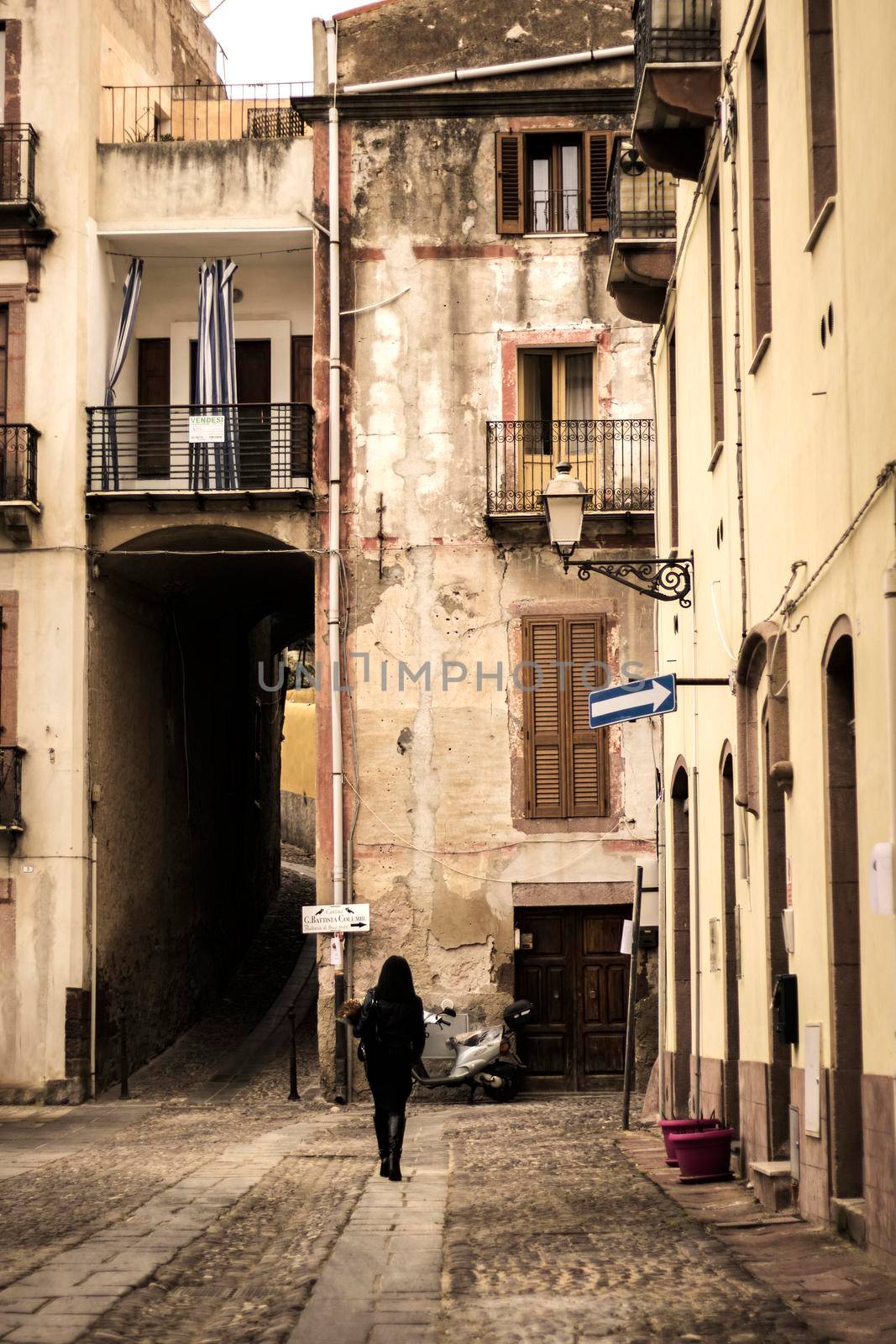 Woman walking in a street in old town in Bosa, a town in Sardegna island in Italy