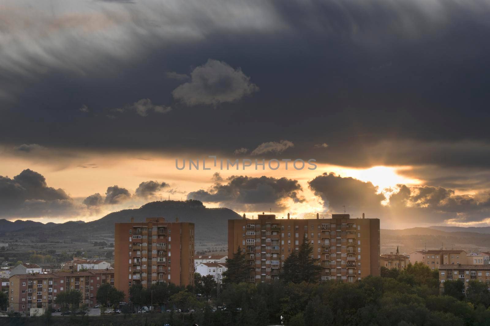 Cloudy sunset over some apartment buildings and a mountain behind in Igualada, a city in Barcelona province