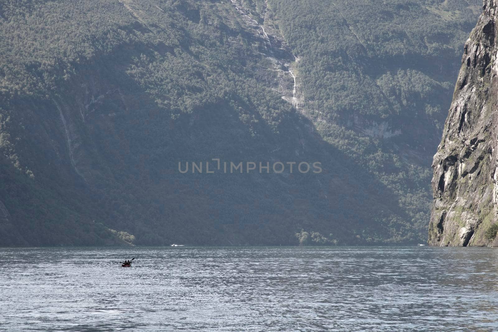 Landscape showing a mountain wall and a canoe on Geiranger fjord in Norway