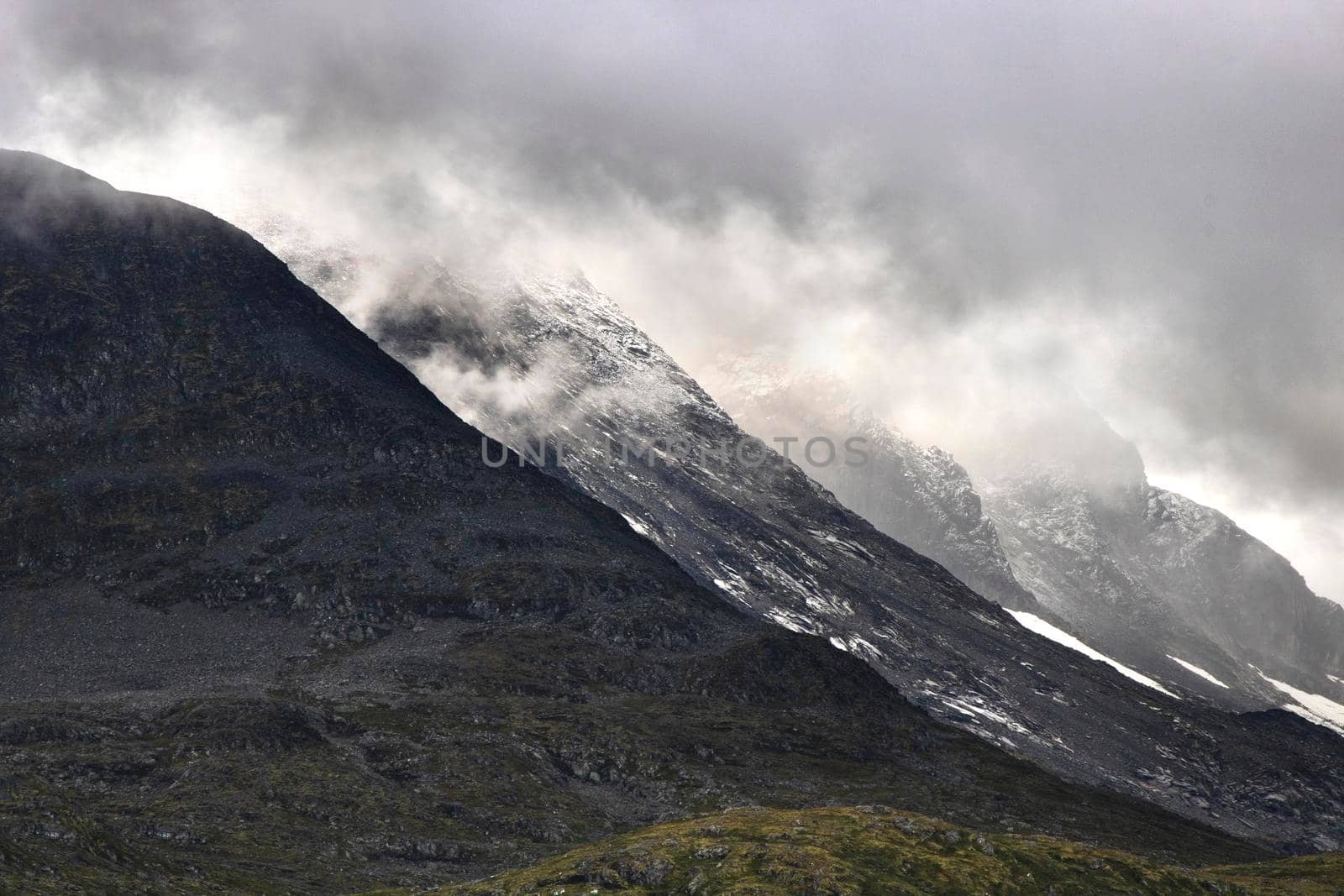 Some snowy mountains aligned under the clouds