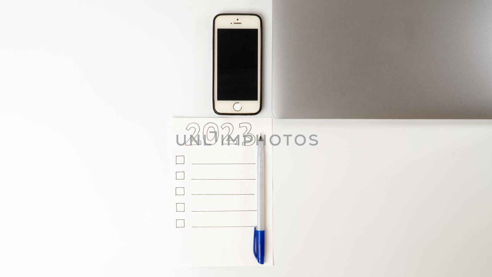 Desktop with laptop and smartphone and to-do list for 2023. High quality photo