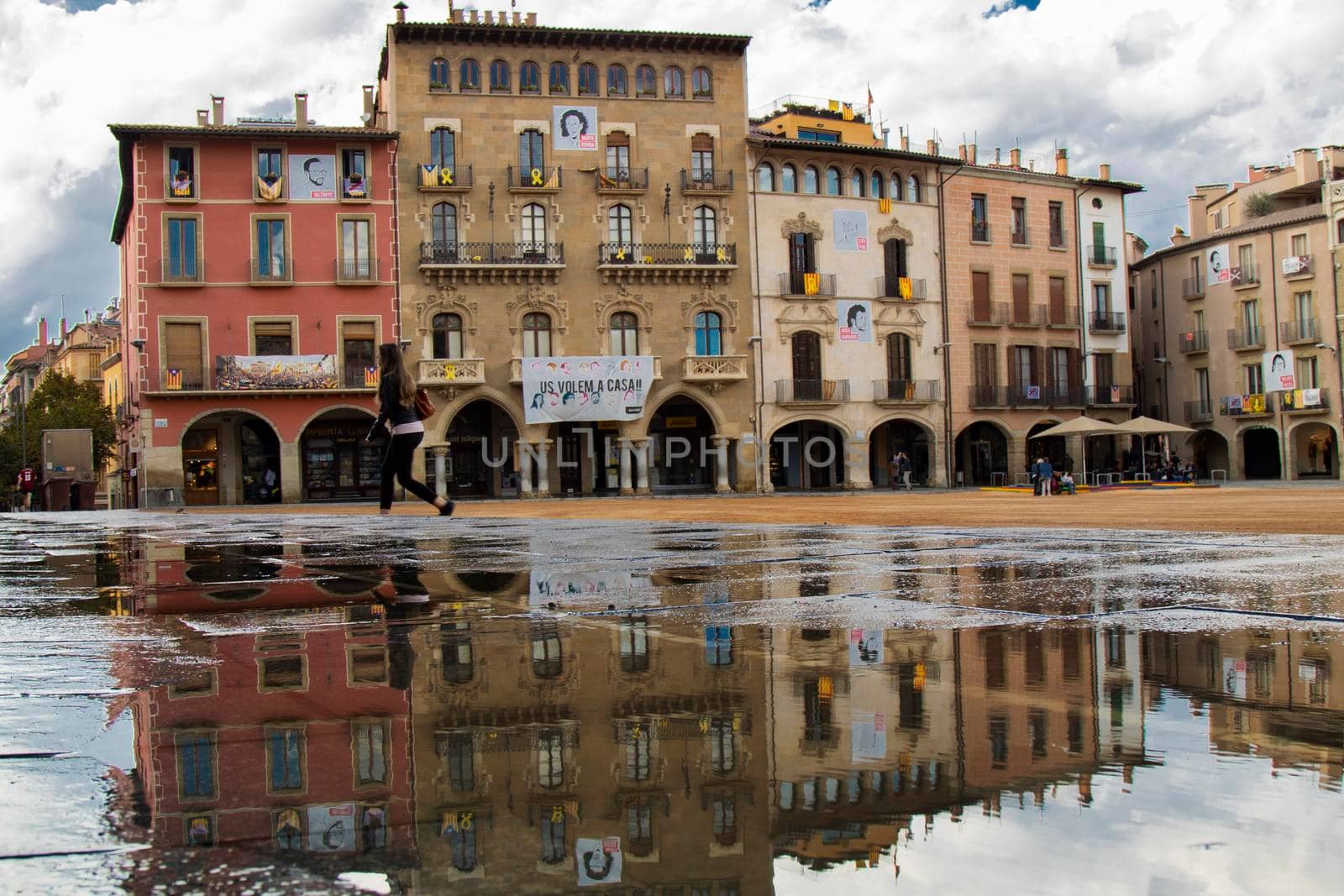 Classic building facades in a square and its reflection on a big puddle in Vic town in Catalonia