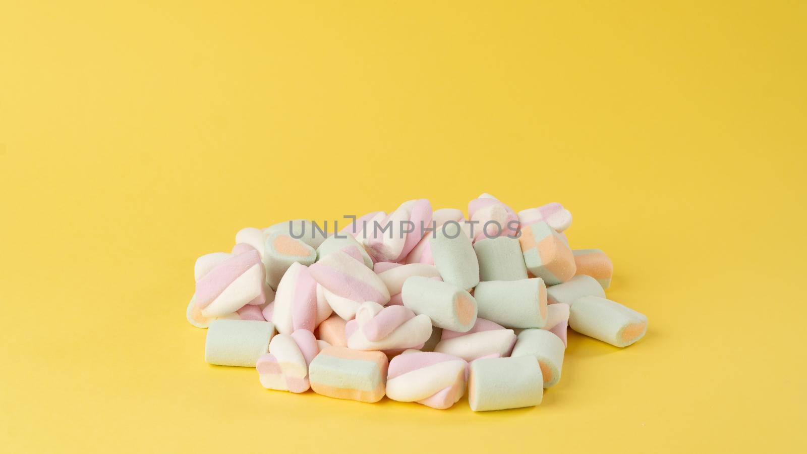 Marshmallows of delicate shades on a bright yellow background. High quality photo