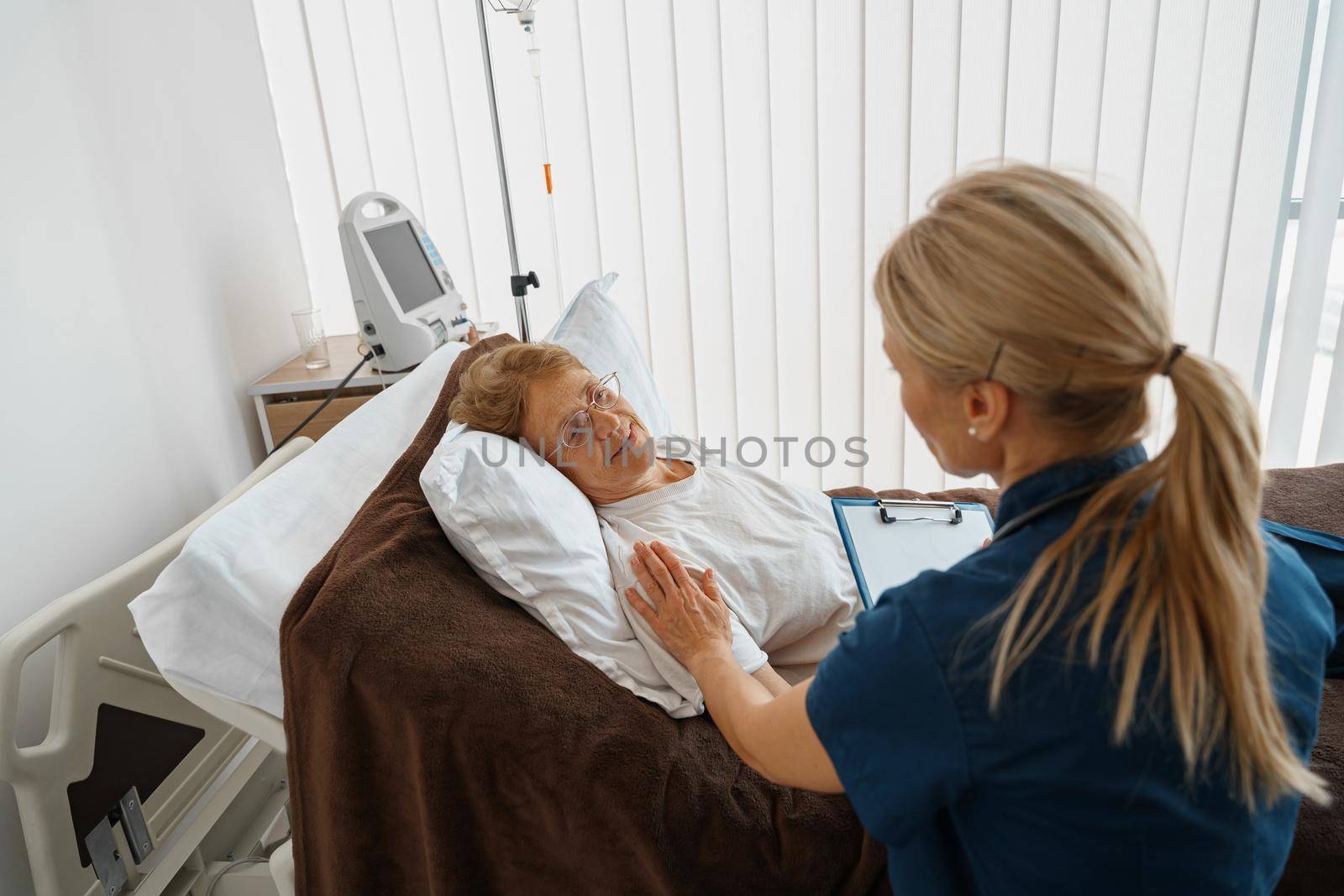 Professional doctor in uniform examines the patient during a visit to hospital ward in clinic