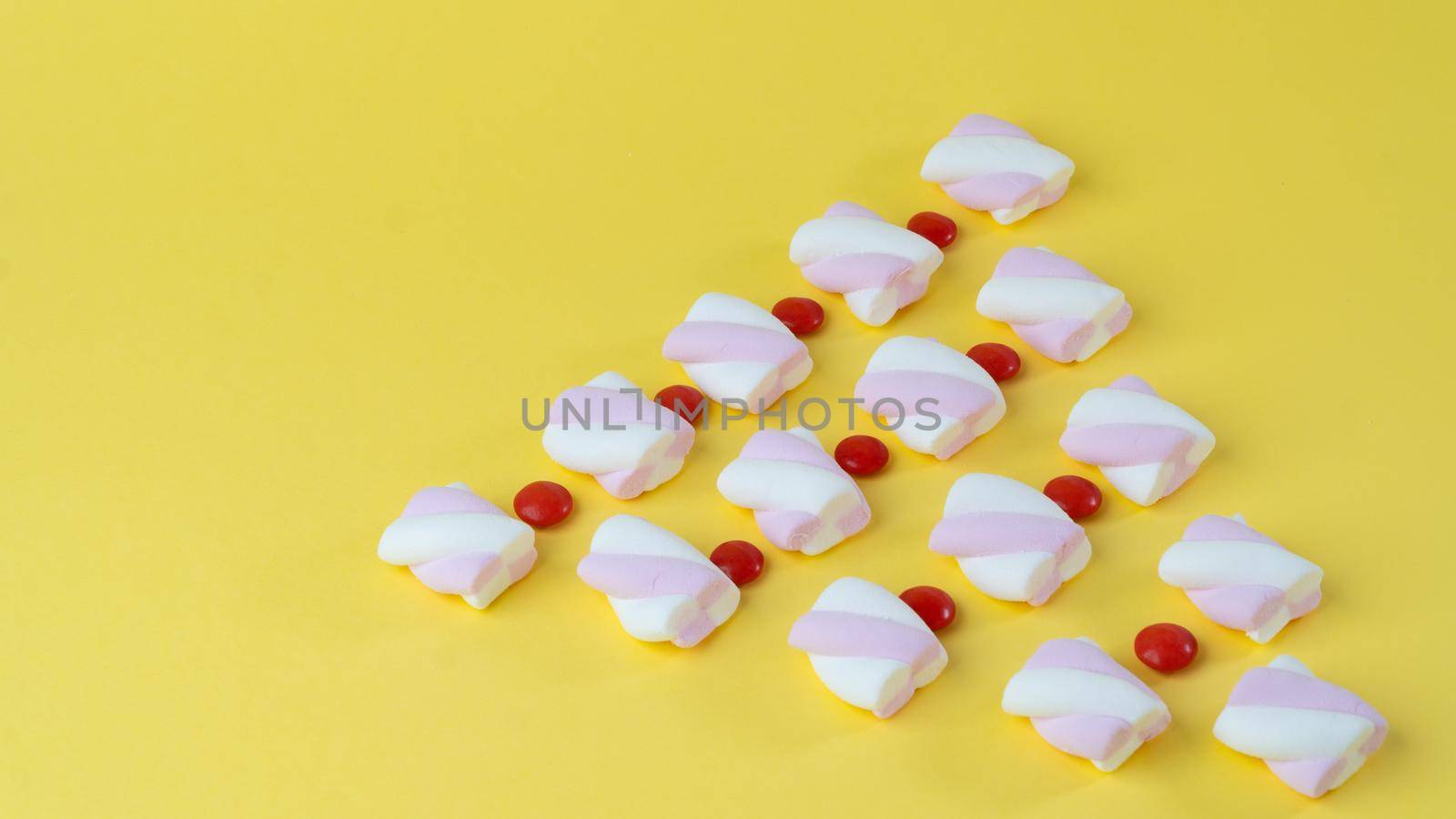 Marshmallows and red candy dragees lined up with a Christmas tree. High quality photo