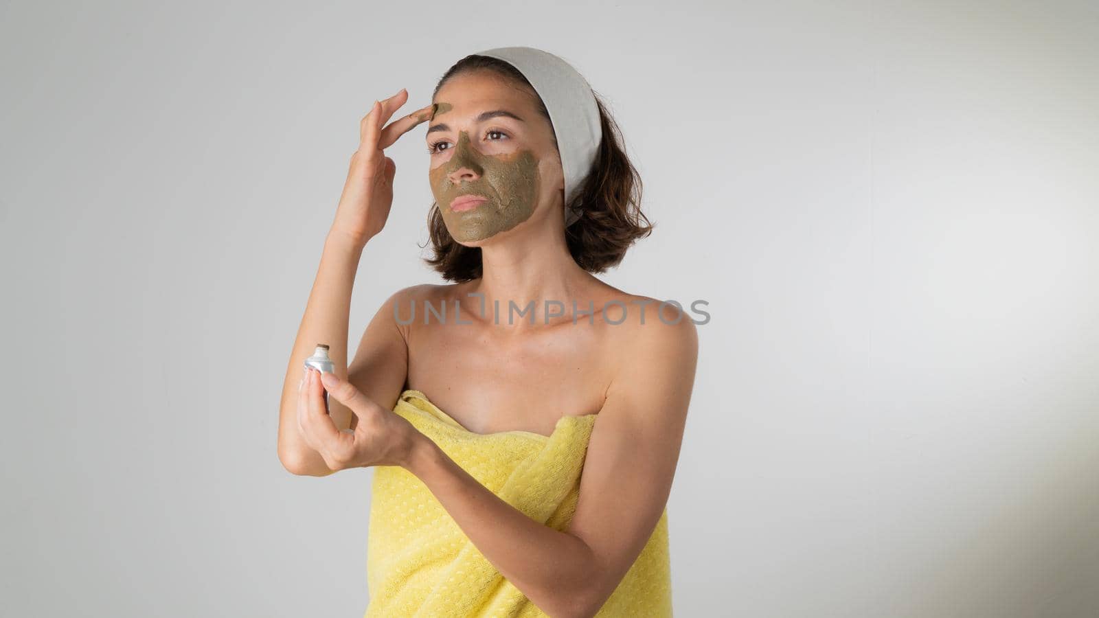 Woman in a towel makes a face mask - home care for the skin of the face by voktybre