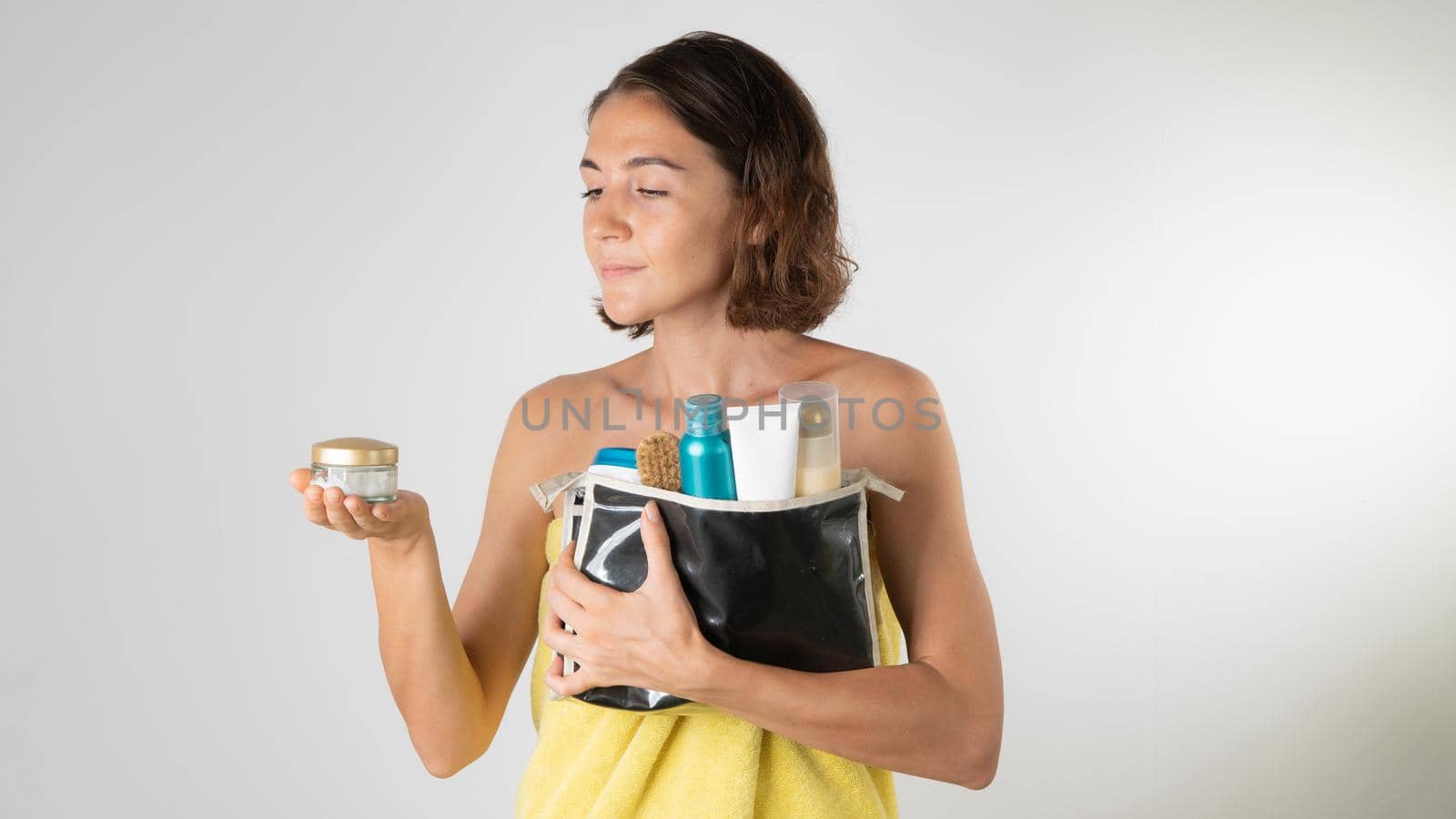 A woman with a cosmetic bag and face cream in her hands after a shower - a procedure for self-care at home. High quality photo