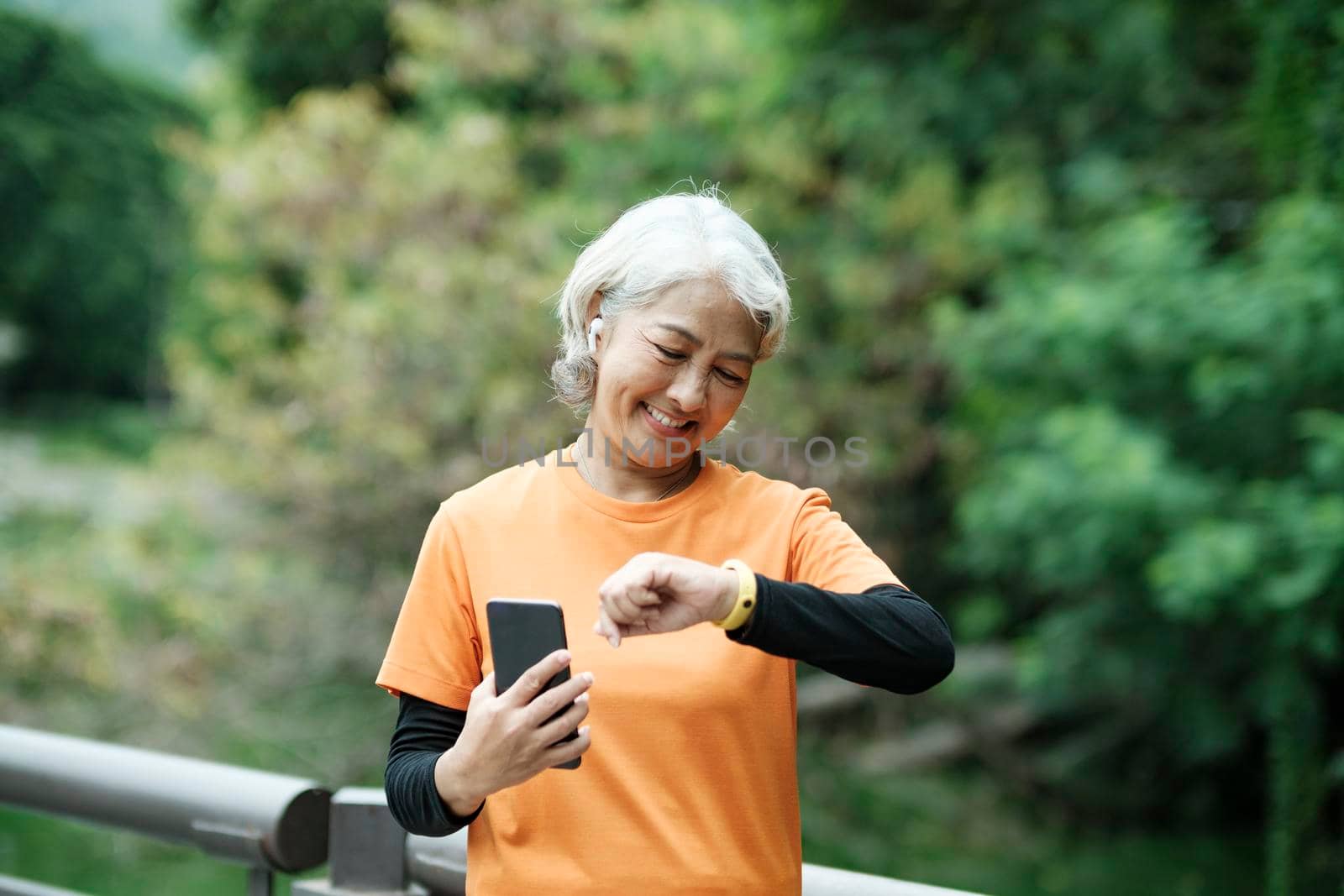 Happy athletic Senior woman checking her smartwatch in the park, Concept of a healthy lifestyle on retirement. health concept.
