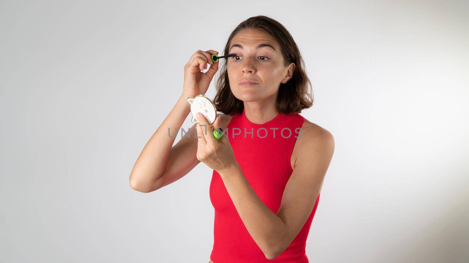 A woman looks in the mirror and dyes her eyelashes with mascara. High quality photo