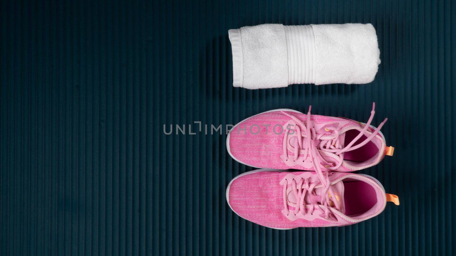 Sneakers and rolled up towel on a workout mat with space for text. High quality photo