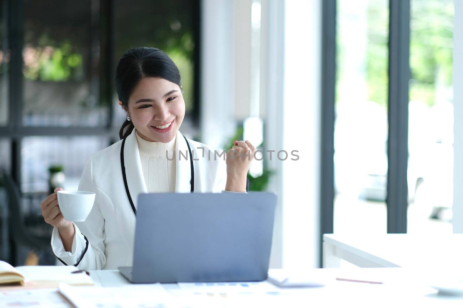 Pretty Asian businesswoman sitting on a laptop And the work came out successfully and the goal was achieved, happy and satisfied with her..