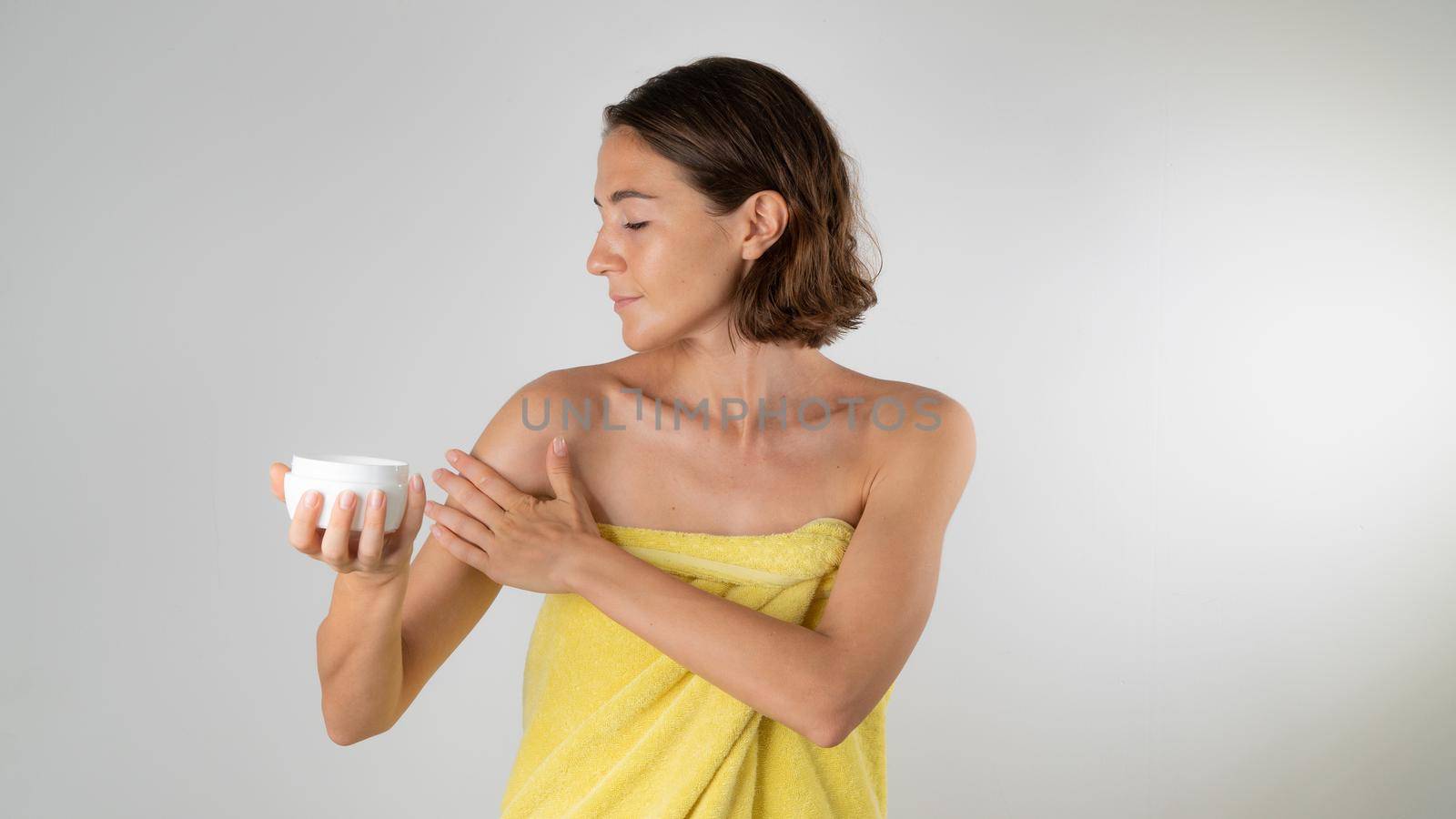 A woman in a towel after a shower applies the cream to the body. High quality photo