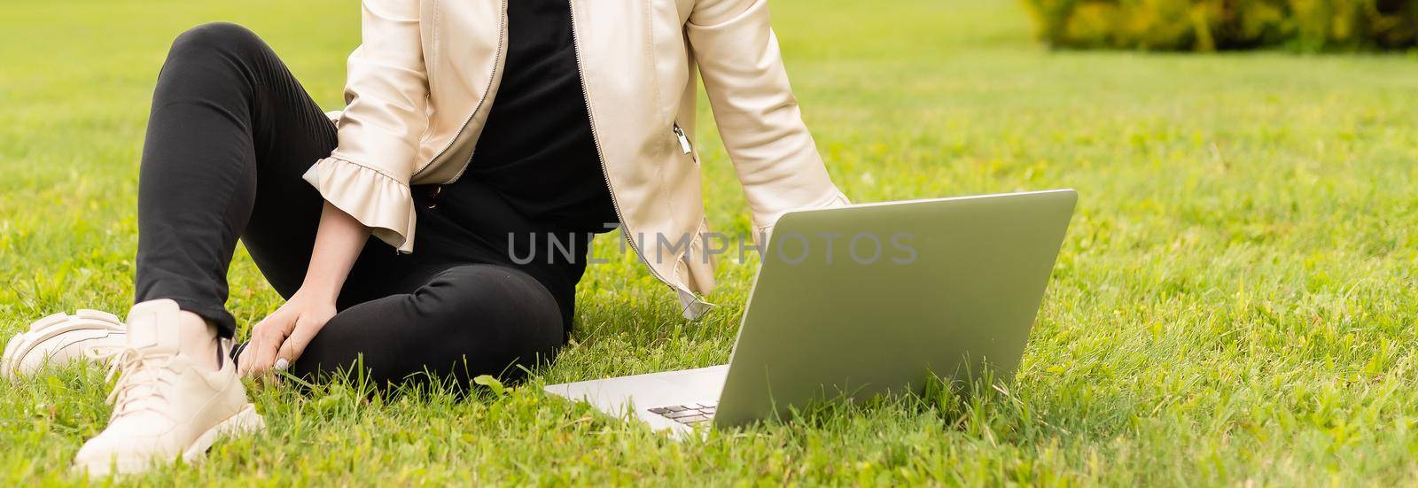 Female copywriter working on laptop in the park, view over the shoulder.