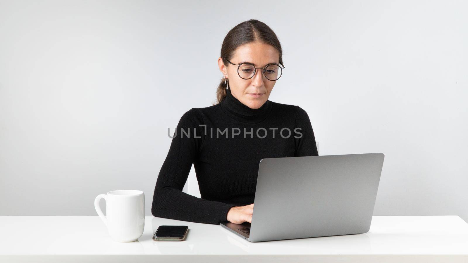 A female office employee works at a laptop by voktybre