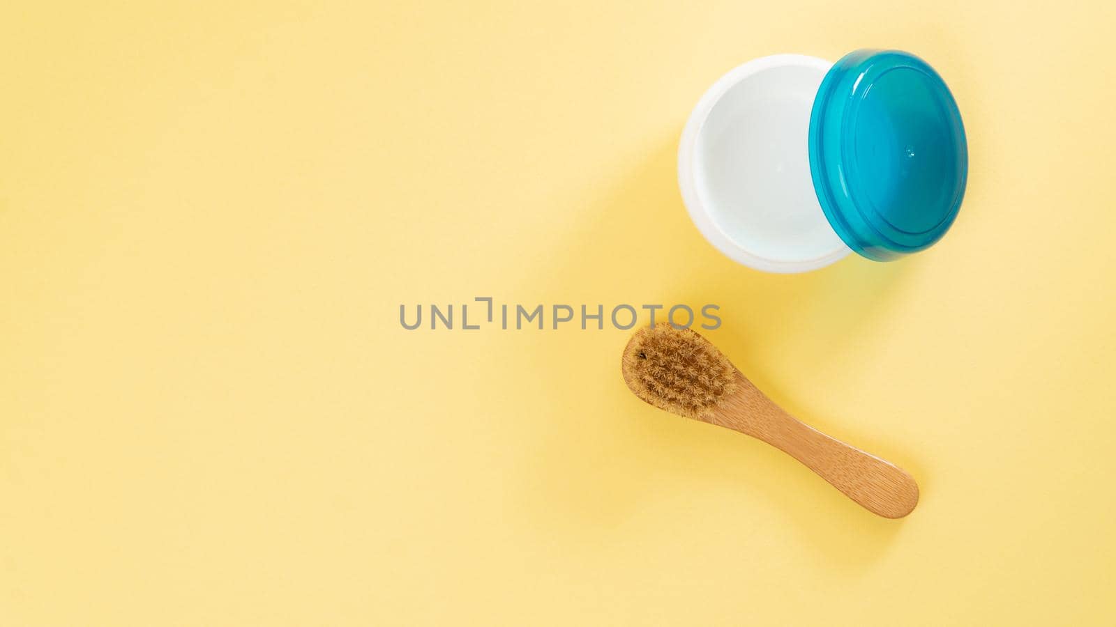 Cream jar and massage brush on a yellow background with text space. High quality photo