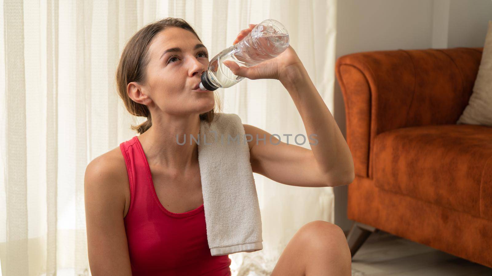 Woman drinks water after home workout, close-up by voktybre