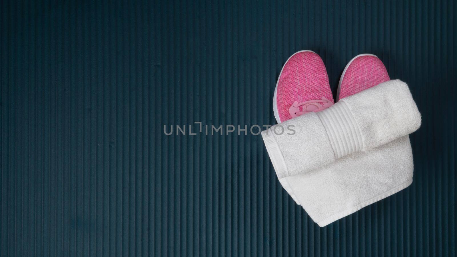 Sneakers and a towel for sports on the mat for training by voktybre