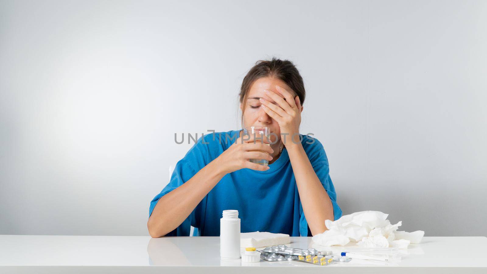 A woman is sick - she drinks water with lemon, pills and a thermometer are on the table by voktybre