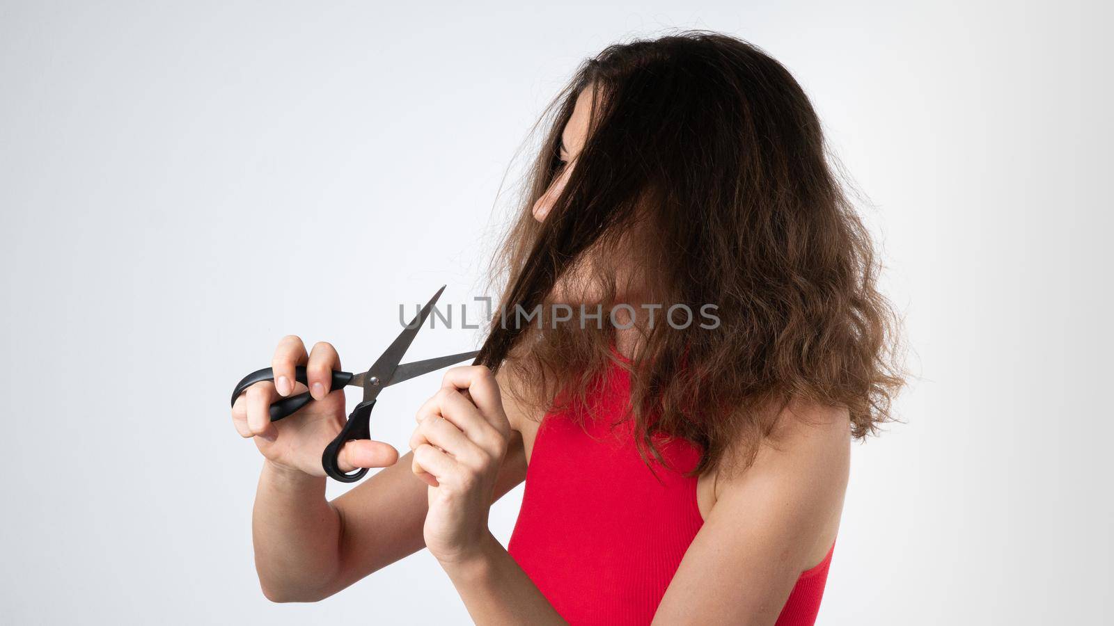 A woman with scissors cuts off the split ends of naughty, unhealthy hair. High quality photo