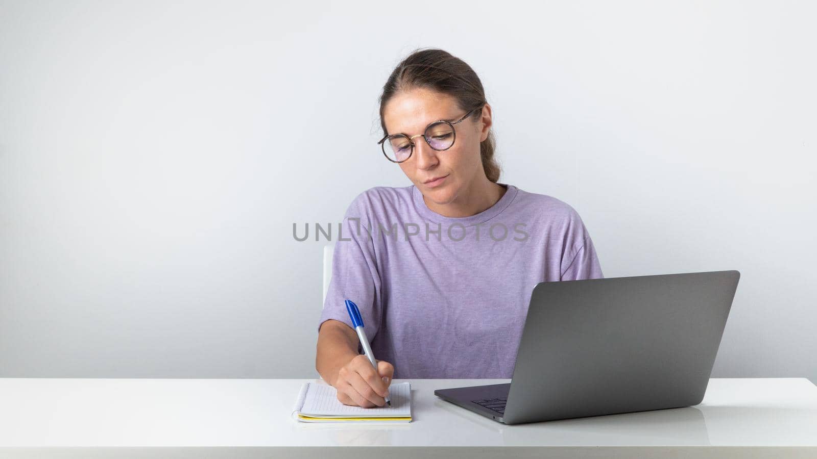 The girl sits at the laptop and makes notes in the notebook, study, work by voktybre