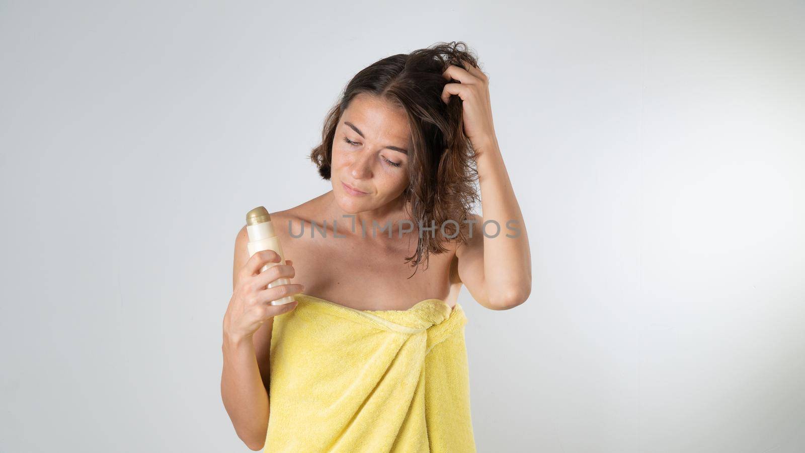 A woman applies serum balm to hair after a shower. High quality photo