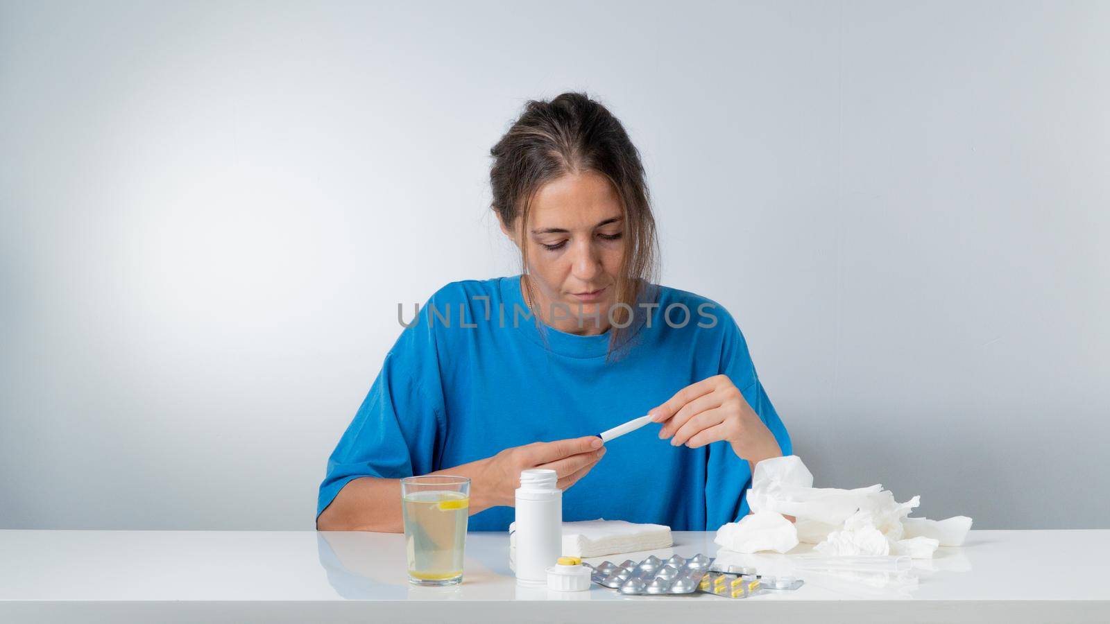 A woman with the flu checks the temperature - treatment at home with pills. High quality photo