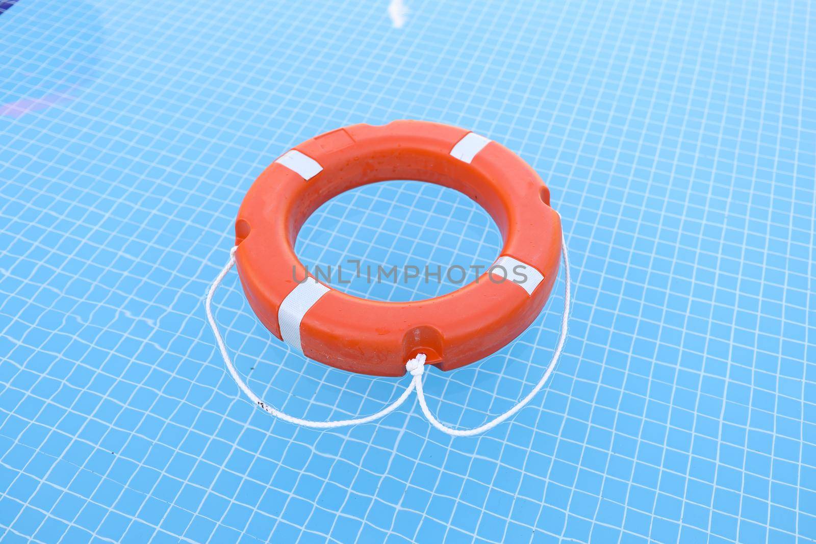 Lifebuoy on blue water with sun glare. Water safety concept