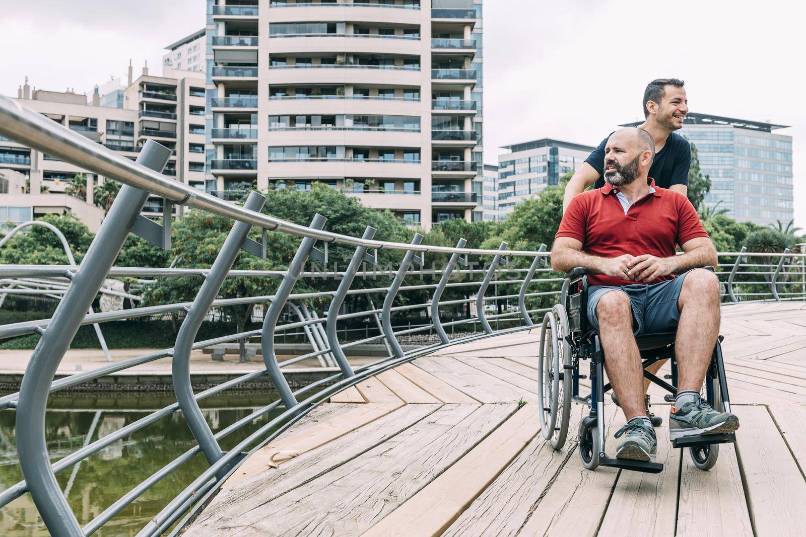 disabled man in wheelchair converses with his friend during a walk, concept of friendship and integration of people with disabilities and reduced mobility problems, vertical photo